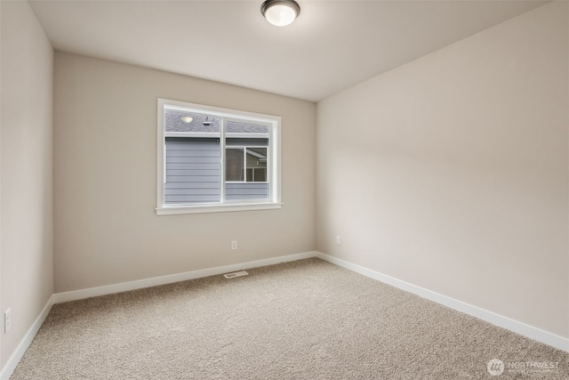 empty room with carpet, visible vents, and baseboards