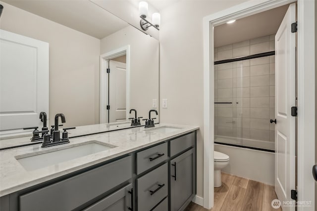 full bath featuring double vanity, wood finished floors, toilet, and a sink