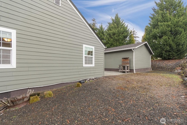 view of property exterior with an outbuilding and a patio