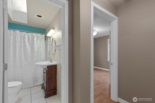 bathroom featuring toilet, tile patterned floors, baseboards, and vanity