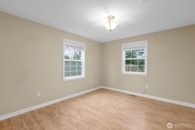 unfurnished room with light wood-style floors, visible vents, and baseboards