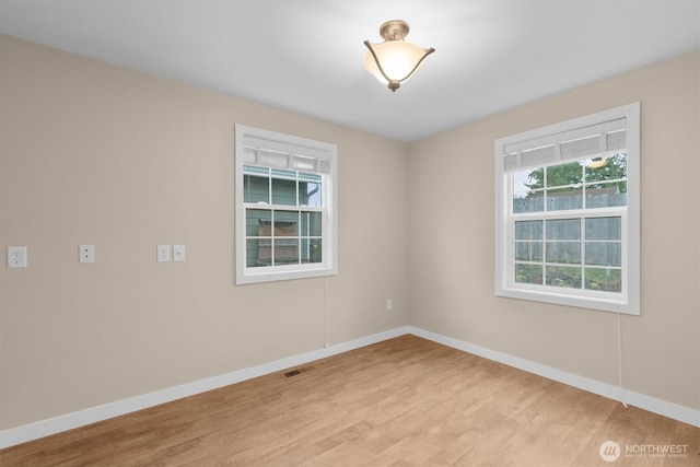 empty room featuring baseboards, visible vents, and light wood-style flooring