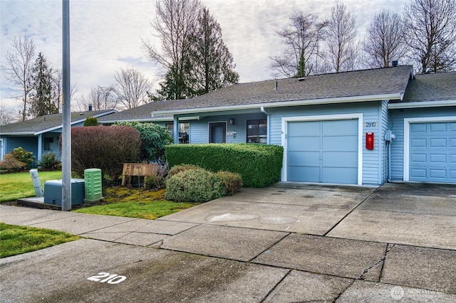 single story home with a front yard, roof with shingles, driveway, and an attached garage