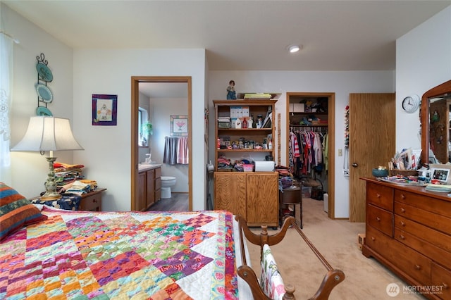 bedroom with a closet, a walk in closet, light colored carpet, and connected bathroom