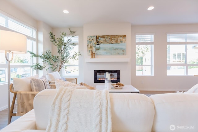 living room featuring recessed lighting, baseboards, and a glass covered fireplace