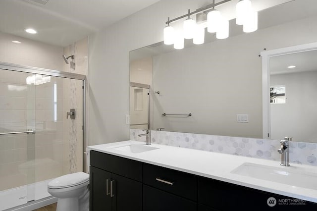 bathroom with toilet, a shower stall, double vanity, and a sink