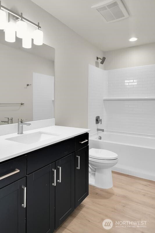 full bath with shower / washtub combination, visible vents, toilet, vanity, and wood finished floors