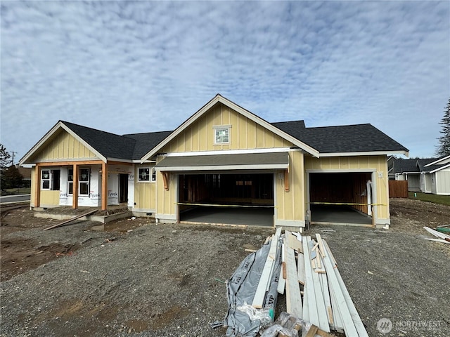 unfinished property with a garage, driveway, and a shingled roof