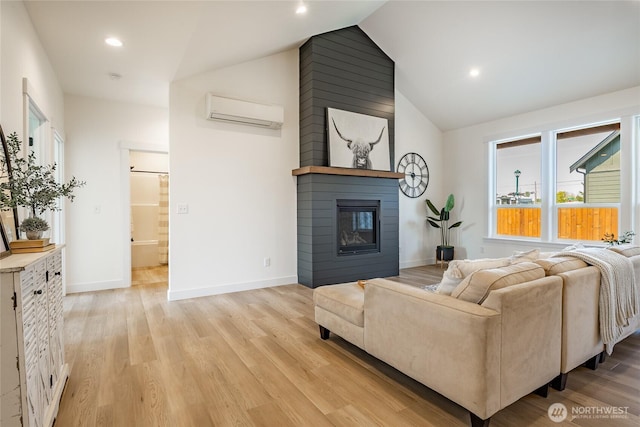 living area with light wood-style flooring, a large fireplace, baseboards, an AC wall unit, and vaulted ceiling