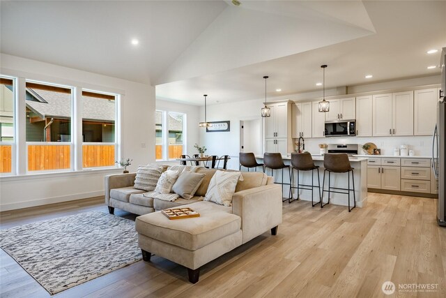 living area with lofted ceiling, light wood-style floors, and recessed lighting