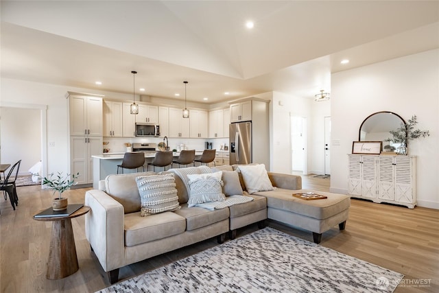living room featuring recessed lighting, light wood finished floors, lofted ceiling, and baseboards