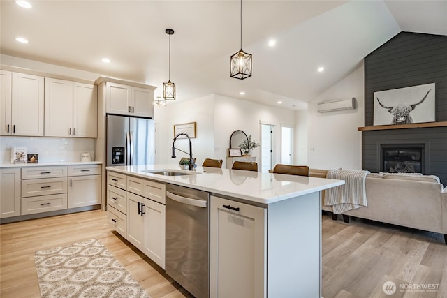 kitchen featuring recessed lighting, light wood-style flooring, stainless steel appliances, an AC wall unit, and a sink