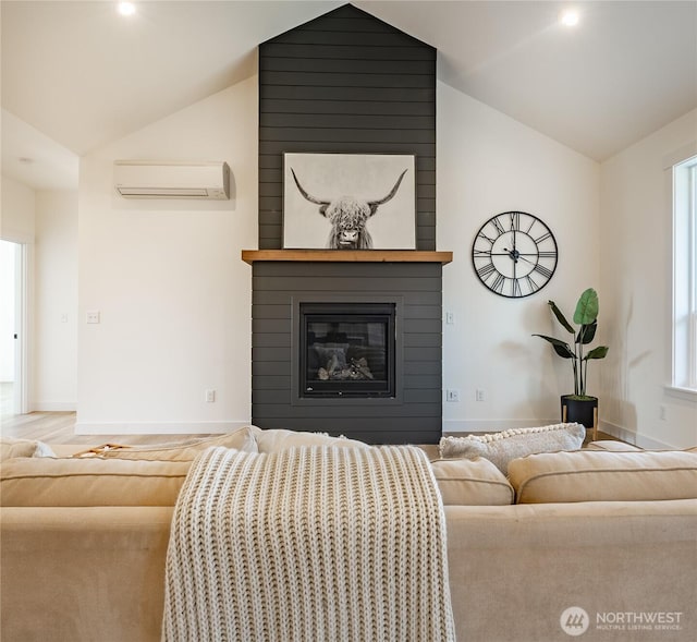 living area featuring lofted ceiling, a large fireplace, a wall unit AC, and baseboards