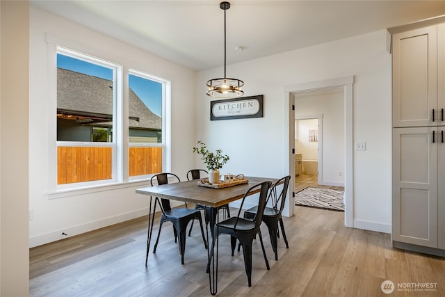 dining space with light wood finished floors, an inviting chandelier, and baseboards