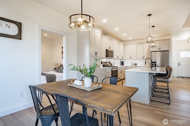 dining room featuring baseboards, recessed lighting, an inviting chandelier, and light wood-style flooring