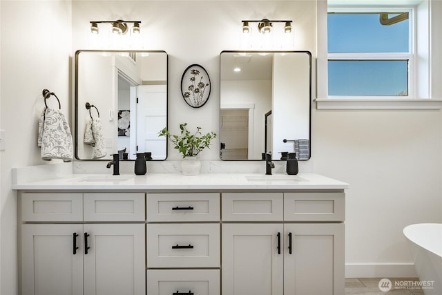 bathroom featuring a freestanding tub, double vanity, and a sink