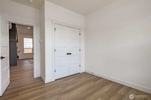 unfurnished bedroom with a closet, light wood-style floors, and baseboards