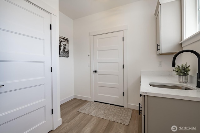 interior space with light wood-type flooring, baseboards, and a sink