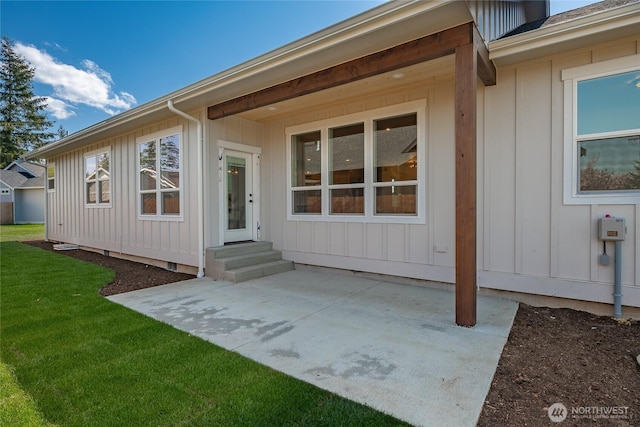 back of house featuring a patio, a lawn, entry steps, and board and batten siding