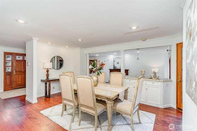 dining space with ornamental molding, recessed lighting, wood finished floors, and ornate columns