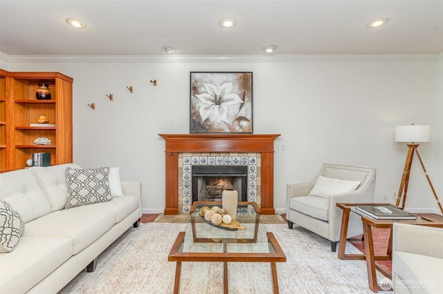 living area featuring a tile fireplace, crown molding, and recessed lighting