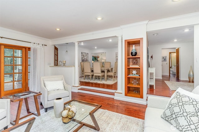 living area with crown molding, recessed lighting, decorative columns, and wood finished floors