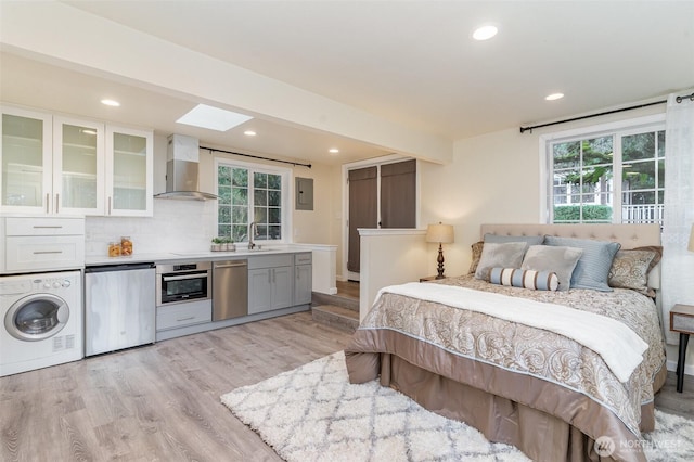 bedroom featuring a skylight, light wood-style floors, a sink, washer / dryer, and fridge