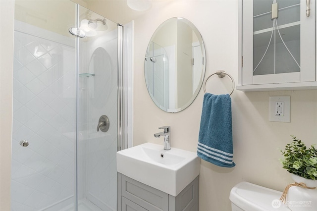 full bathroom with vanity, a shower stall, and toilet