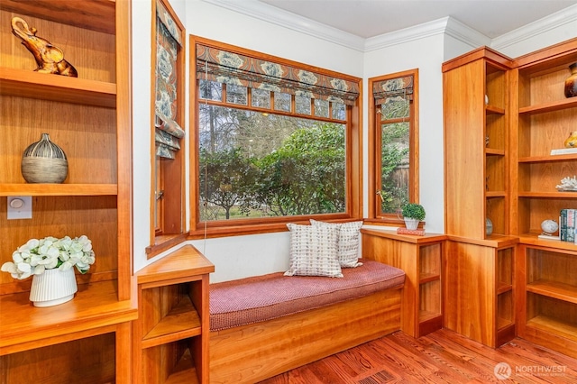 living area with ornamental molding and wood finished floors