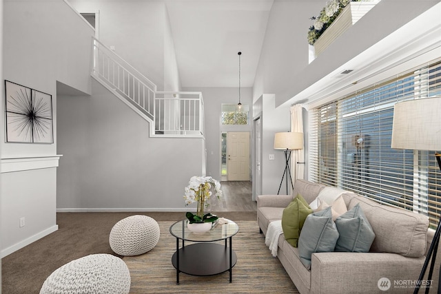 living area featuring a high ceiling, stairway, and baseboards