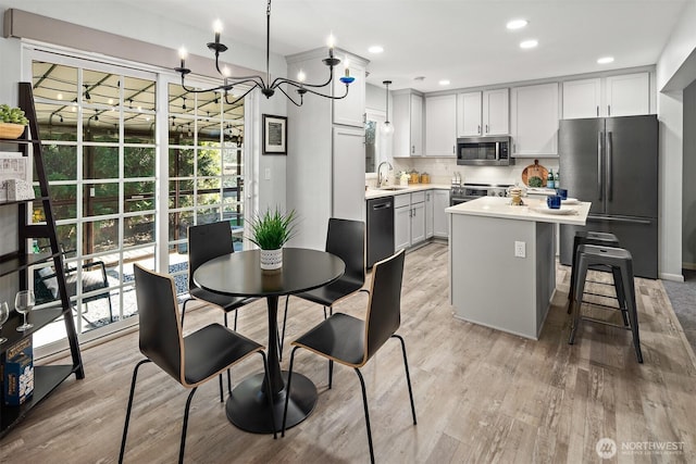 kitchen with a sink, stainless steel appliances, light countertops, light wood-style floors, and backsplash