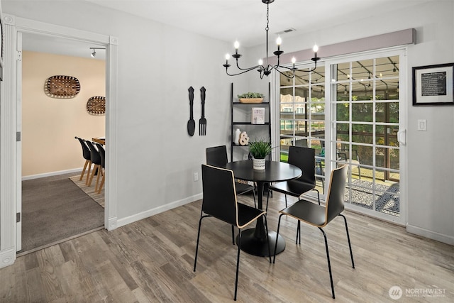 dining area featuring an inviting chandelier, baseboards, and wood finished floors