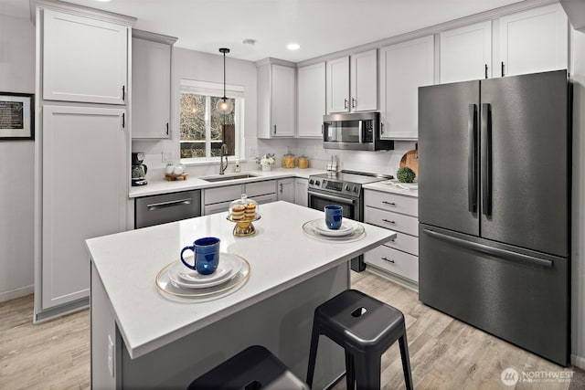 kitchen featuring stainless steel appliances, light wood-type flooring, gray cabinets, and a sink