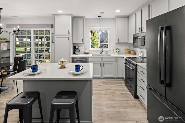 kitchen featuring electric range, a sink, freestanding refrigerator, stainless steel microwave, and a kitchen bar