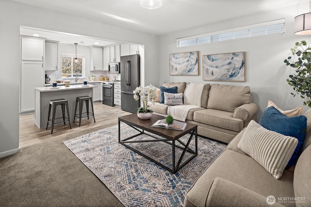 living area featuring light carpet, light wood-style flooring, and recessed lighting