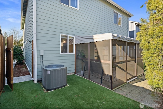 rear view of property with a yard, a sunroom, and central air condition unit