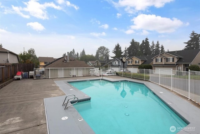 pool with a patio area, fence, and a residential view