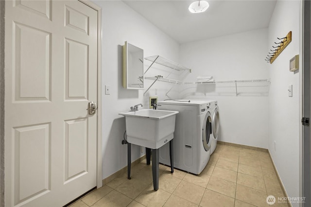 clothes washing area with laundry area, light tile patterned flooring, baseboards, and washer and clothes dryer