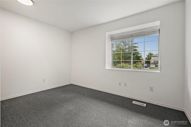 unfurnished room with dark colored carpet, visible vents, and baseboards