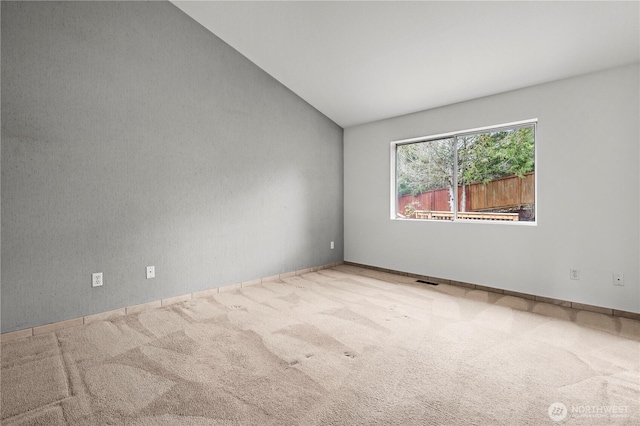 carpeted spare room with visible vents and lofted ceiling