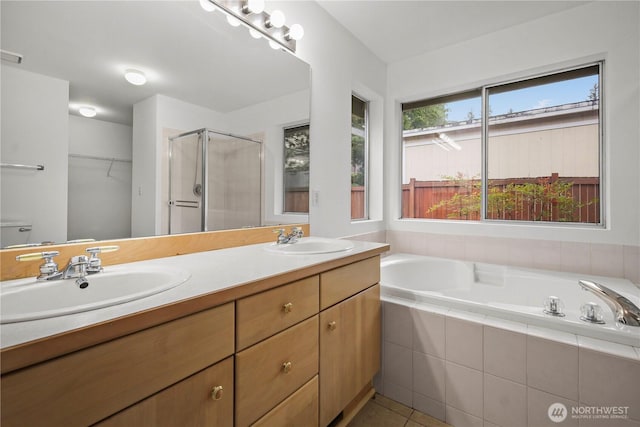 full bathroom featuring a shower stall, a garden tub, double vanity, and a sink