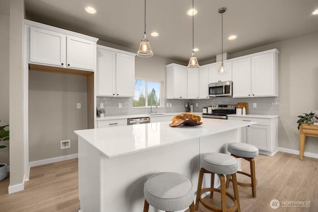 kitchen featuring light wood-style flooring, white cabinetry, stainless steel appliances, and a sink