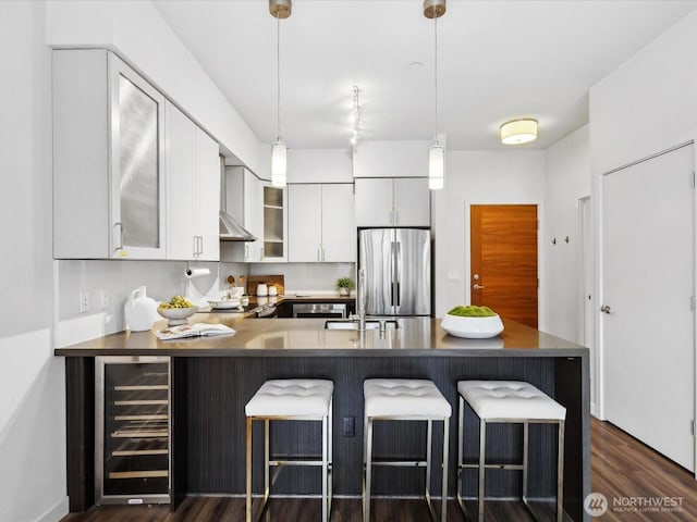 kitchen featuring beverage cooler, glass insert cabinets, freestanding refrigerator, a peninsula, and white cabinetry