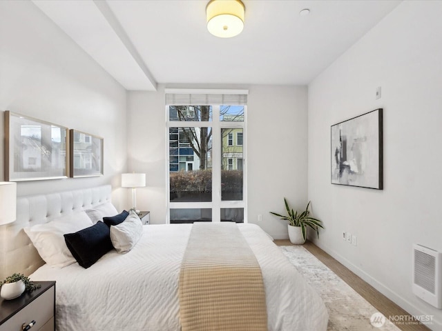 bedroom with heating unit, baseboards, and wood finished floors