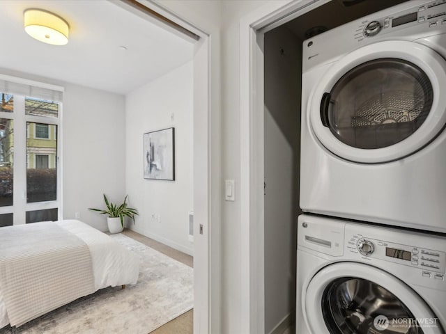 laundry room with baseboards and stacked washer / drying machine