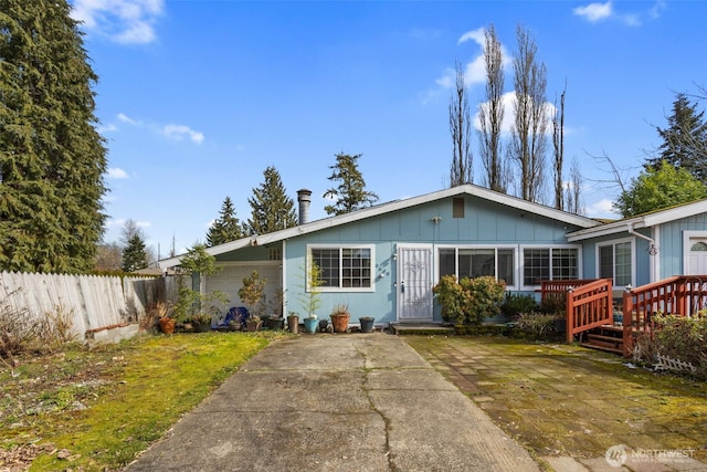 view of front of property with board and batten siding, concrete driveway, fence, and an attached garage