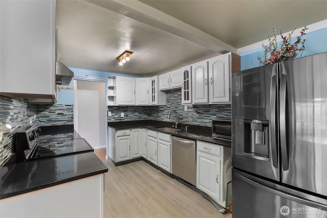 kitchen featuring open shelves, stainless steel appliances, a sink, wall chimney range hood, and light wood-type flooring