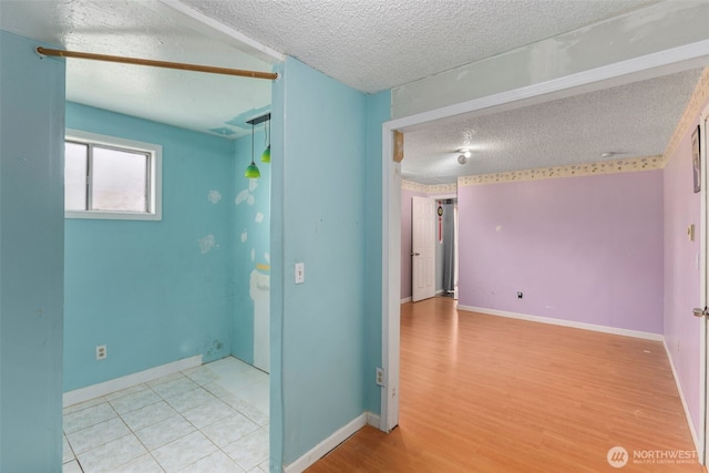 unfurnished room with a textured ceiling, baseboards, and wood finished floors