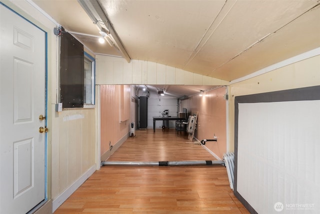 corridor with lofted ceiling, light wood finished floors, and radiator