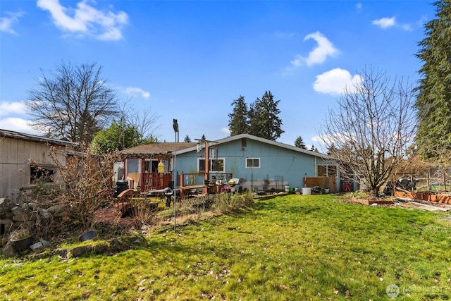 back of property featuring a wooden deck and a yard